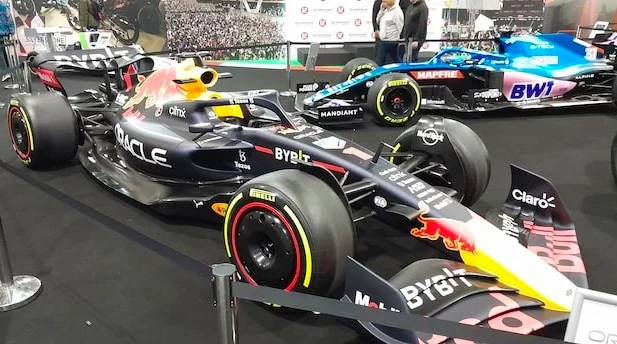 2022 Red Bull F1 show car in the foreground with a 2021 Alpine F1 show car in the background.