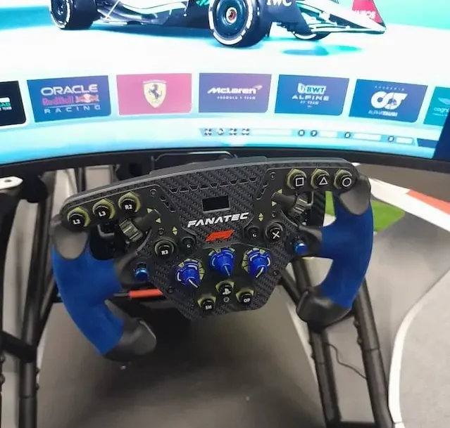 Fanatec Podium F1 sim racing wheel with a monitor in the background showing a Formula 1 car from a game.