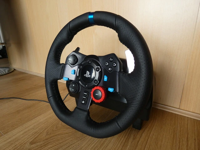 Logitech G29 sim racing wheel on a wooden floor with a wooden background.