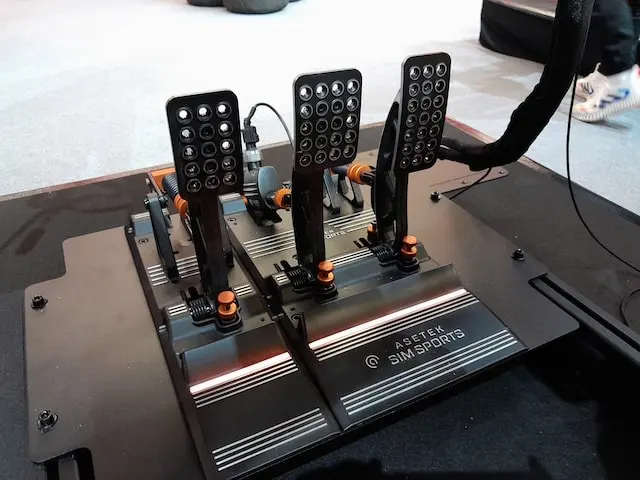 Asetek Invicta sim racing pedals mounted to a pedal board, showing the gas, brake and clutch pedals.