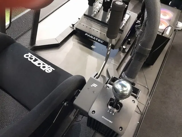 Fanatec ClubSport SQ V1.5 sim racing shifter mounted alongside a ClubSport handbrake with CSL pedals and a Sparco racing seat in the background.