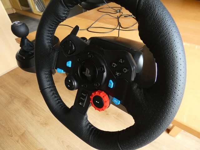 Logitech G29 sim racing wheel on a wooden table next to the Logitech Driving Force gear shifter.