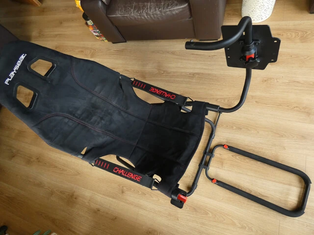 Playseat Challenge sim racing rig on a wooden floor showing the wheel mount lifted up to allow you to get in and out of the seat.