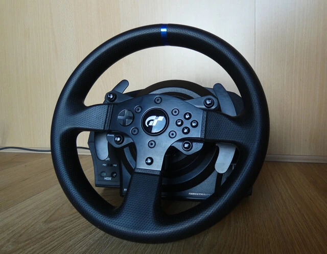 Thrustmaster T300 RS GT Edition sim racing wheel and wheel base with a wooden background.