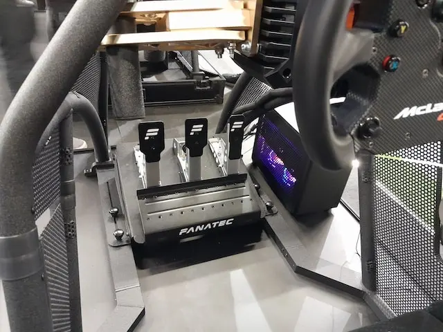 Fanatec CSL sim racing pedals with upgraded face plates on a Rennsport cockpit V2 next to a sim racing PC and connected to a CSL DD wheel base and McLaren GT3 V2 wheel rim.