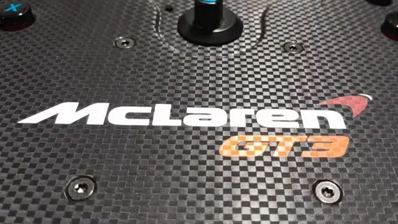 Close up of the Fanatec McLaren GT3 V2 sim racing wheel showing the logo and the false carbon fiber face plate.