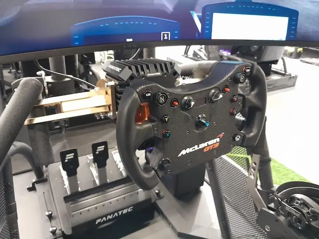 Fanatec CSL DD sim racing wheel base mounted to a rig with Podium brackets, connected to a CSL Elite McLaren GT3 V2 wheel rim and CSL pedals in the background.