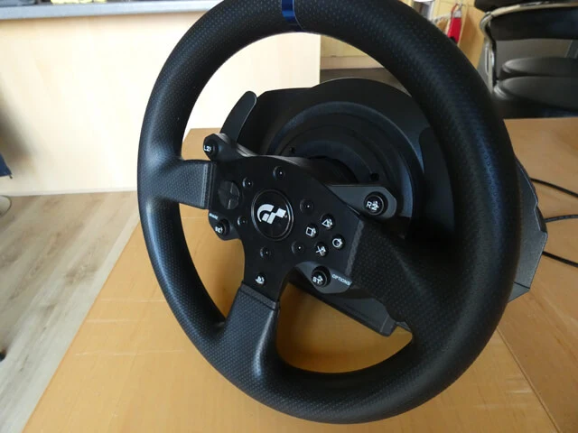 Thrustmaster T300 RS wheel rim and base sitting on a wooden table.